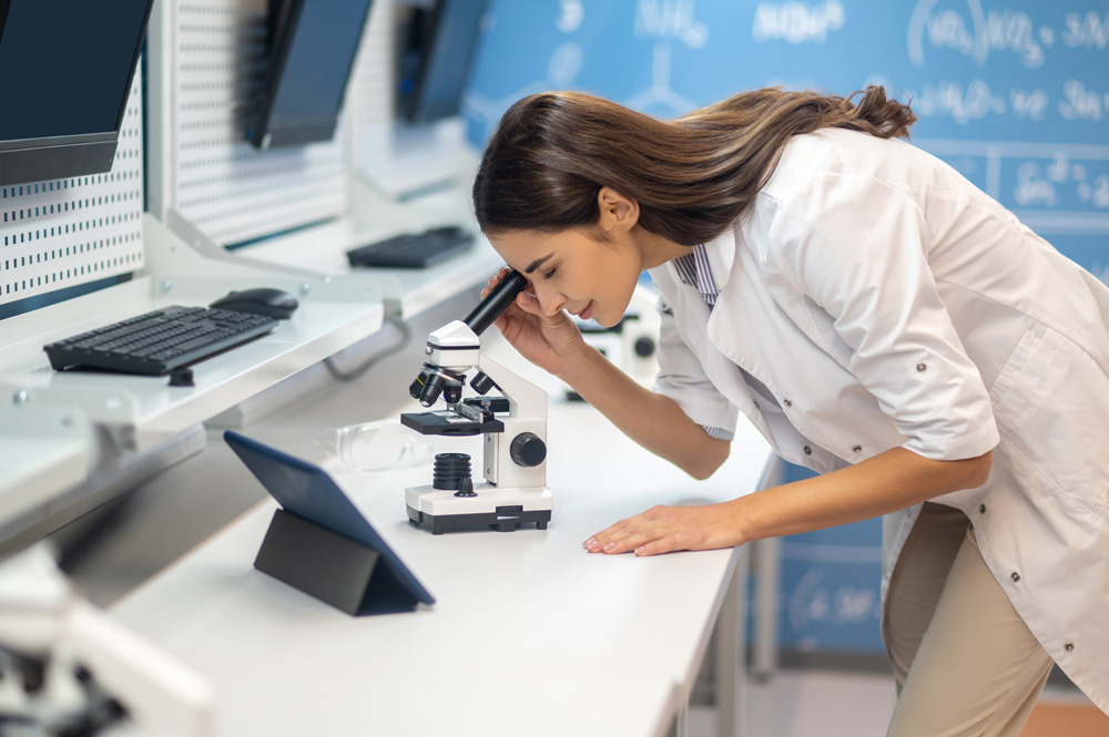 woman looking through microscope